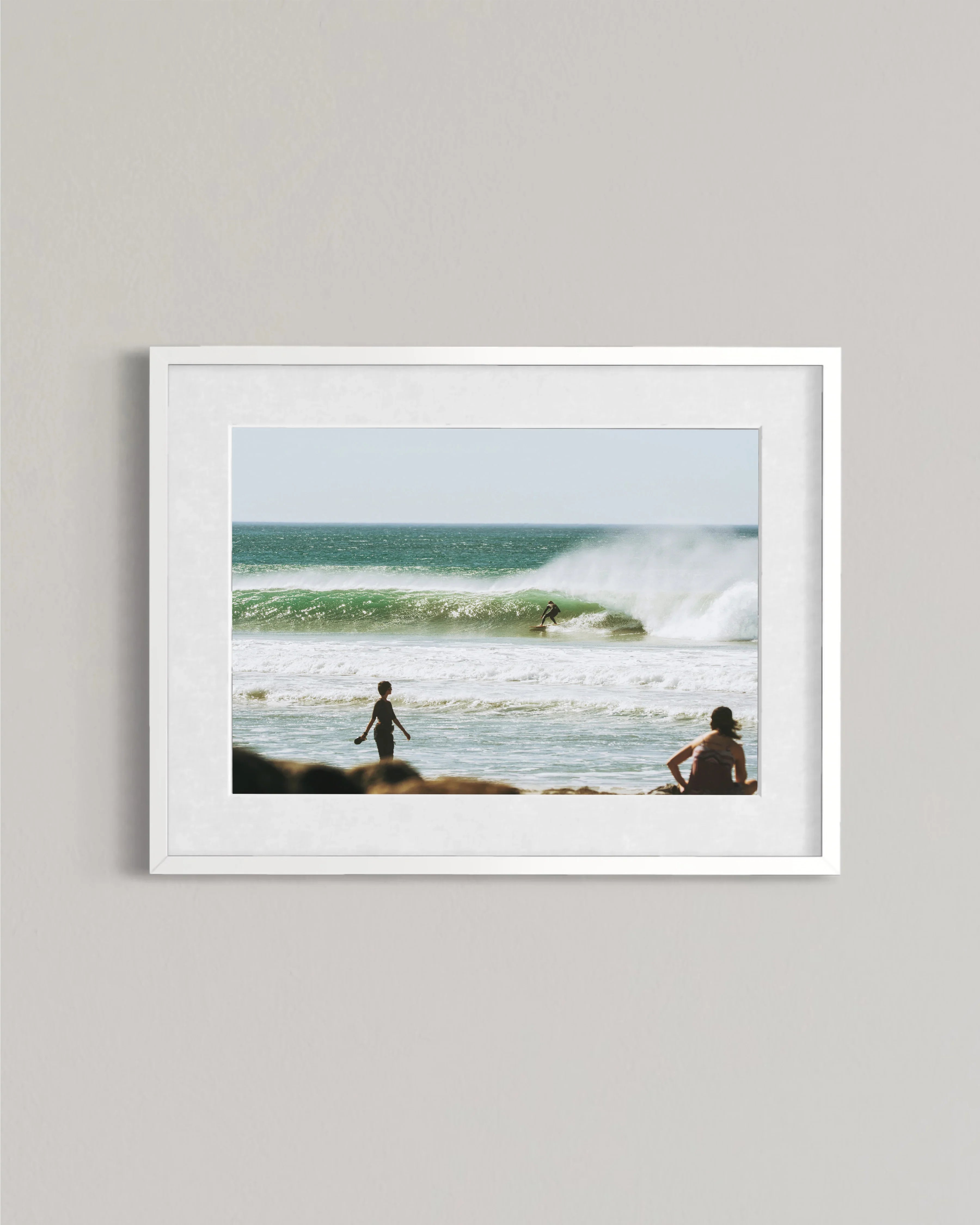 Framed photo of surfer riding a wave in ocean with two people watching on shore