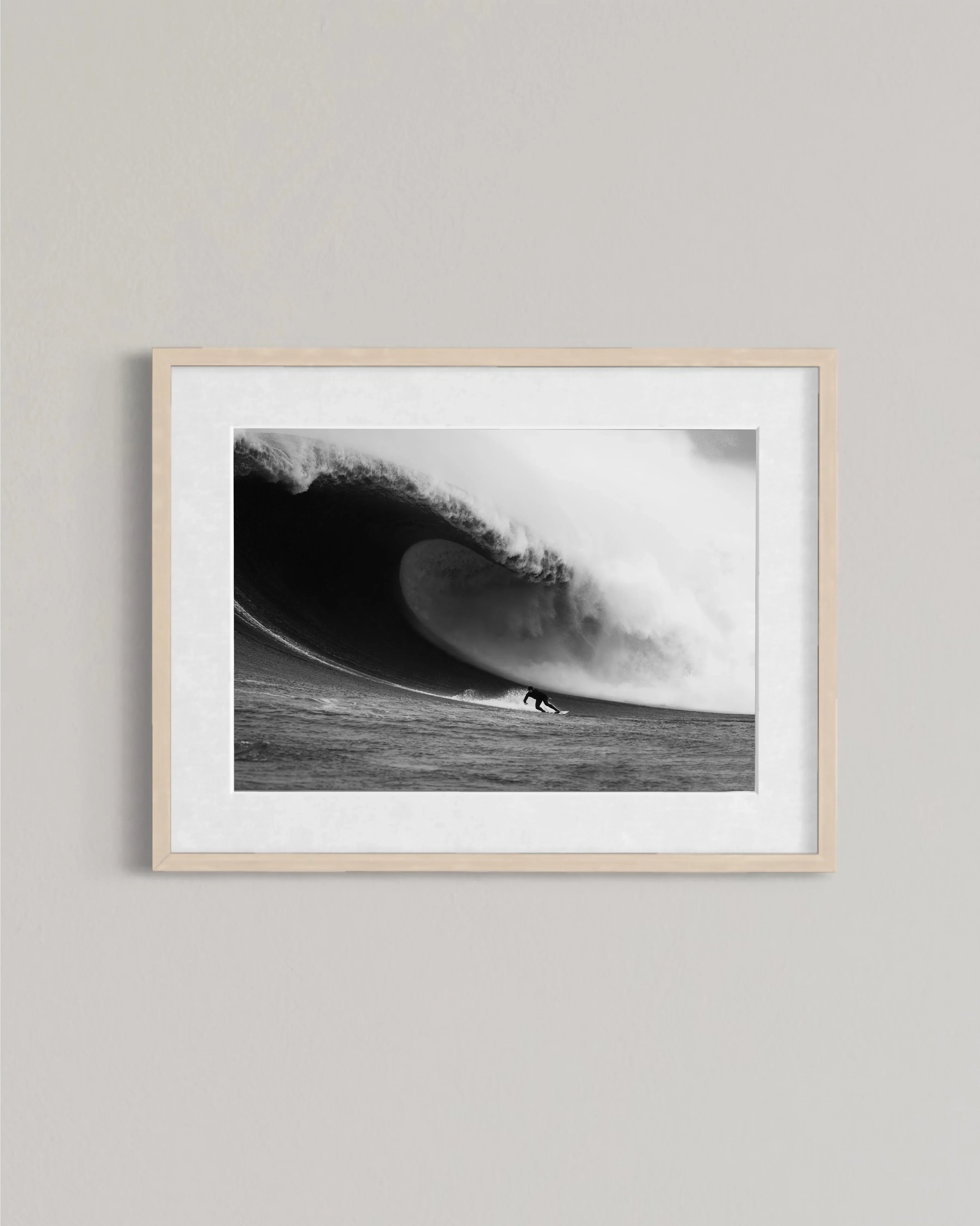 Black and white framed photo of a surfer riding a large powerful wave on the ocean wall