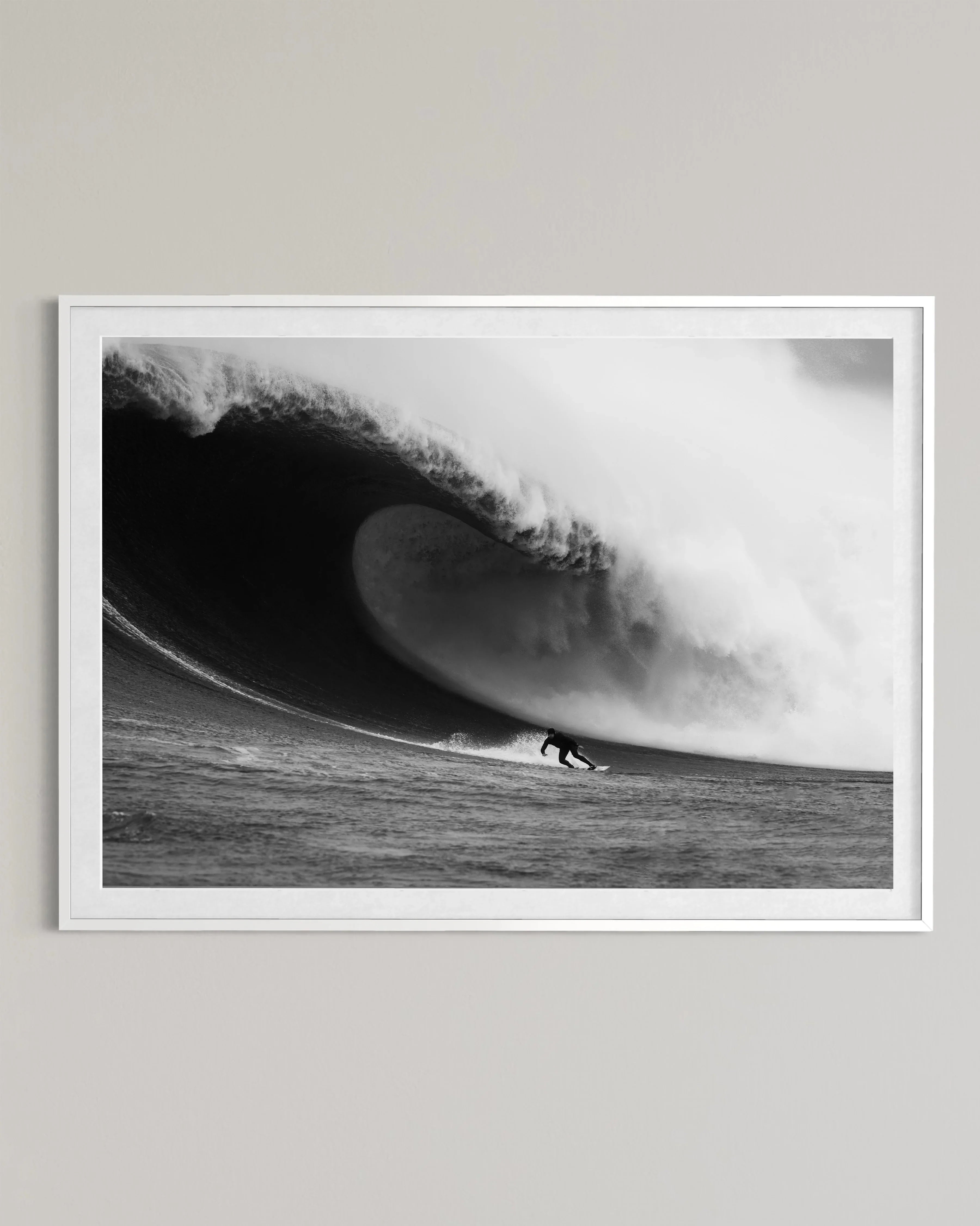 Black and white photo of surfer riding large curling ocean wave framed on wall