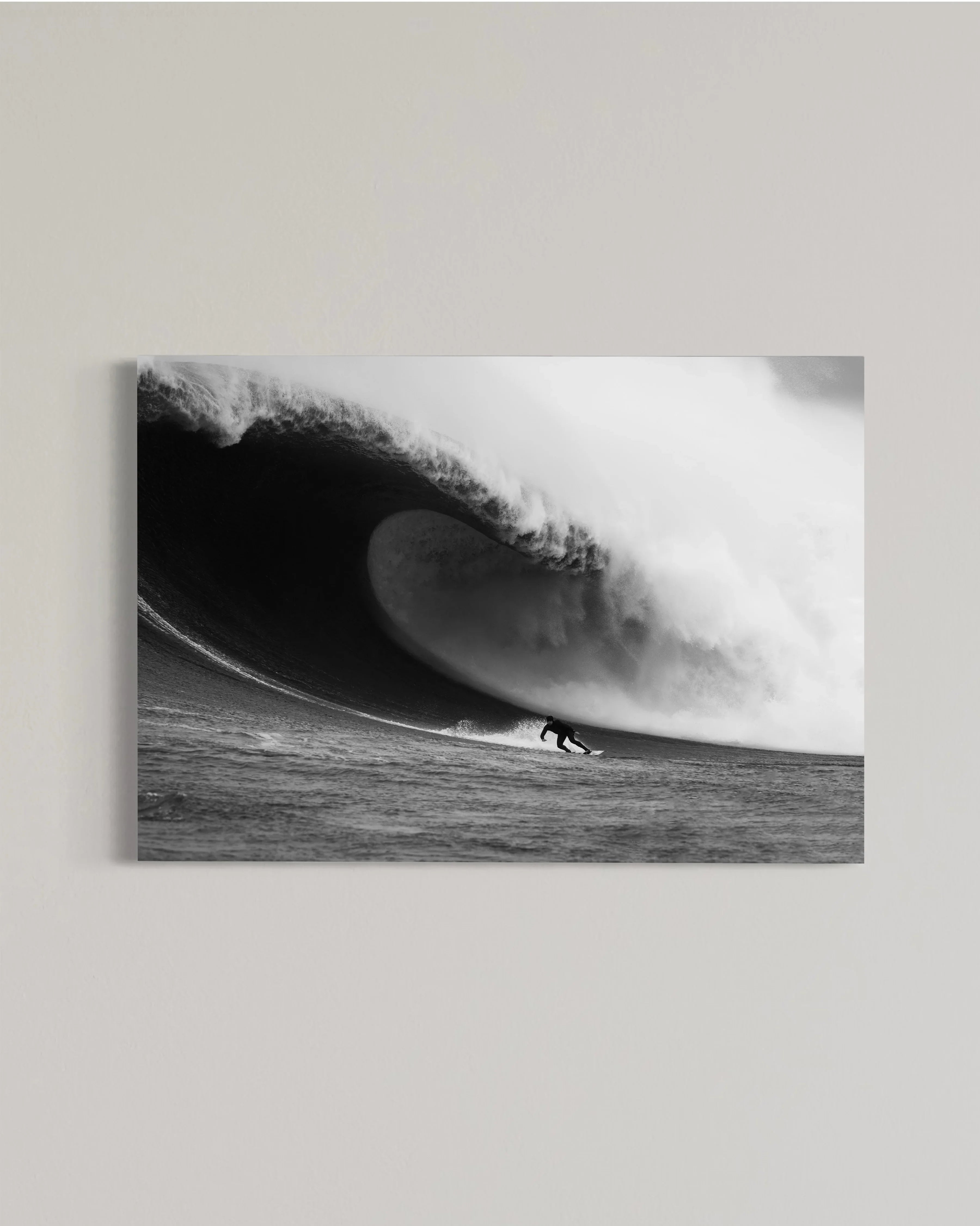 Black and white photo of a surfer riding a large powerful ocean wave curling overhead