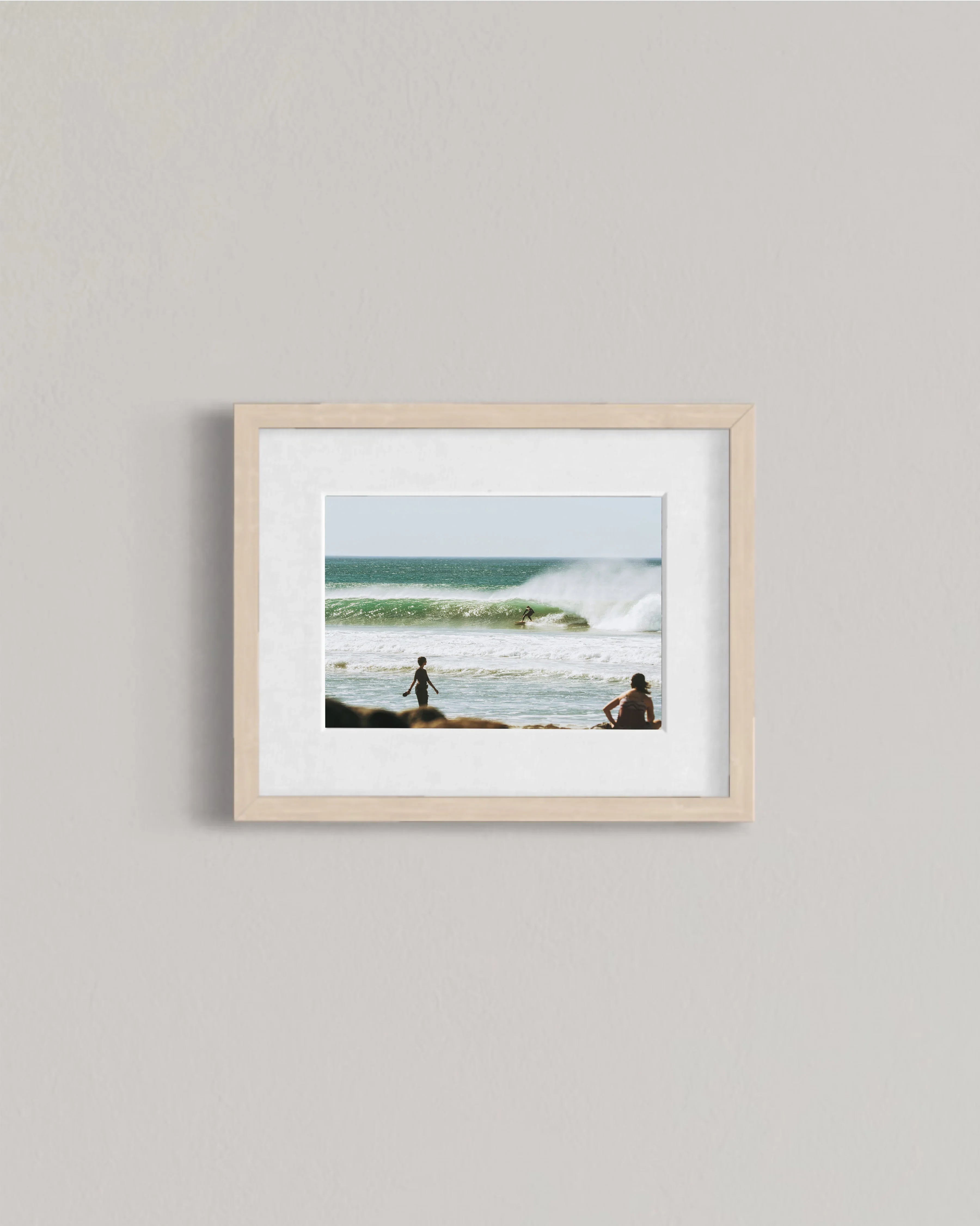 Framed photo of surfer riding a wave with two people watching on the beach