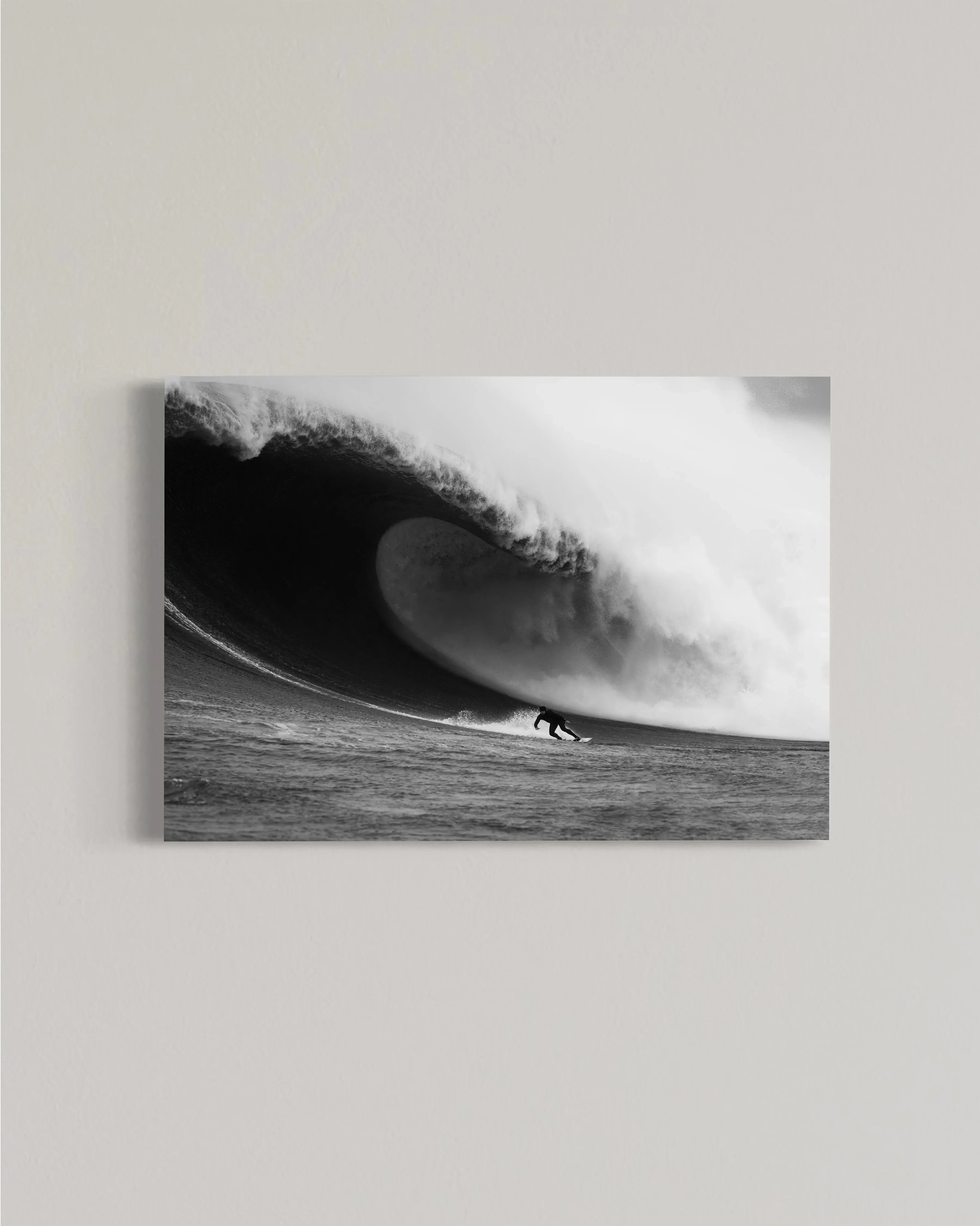 Black and white photo of surfer riding a large powerful wave in ocean