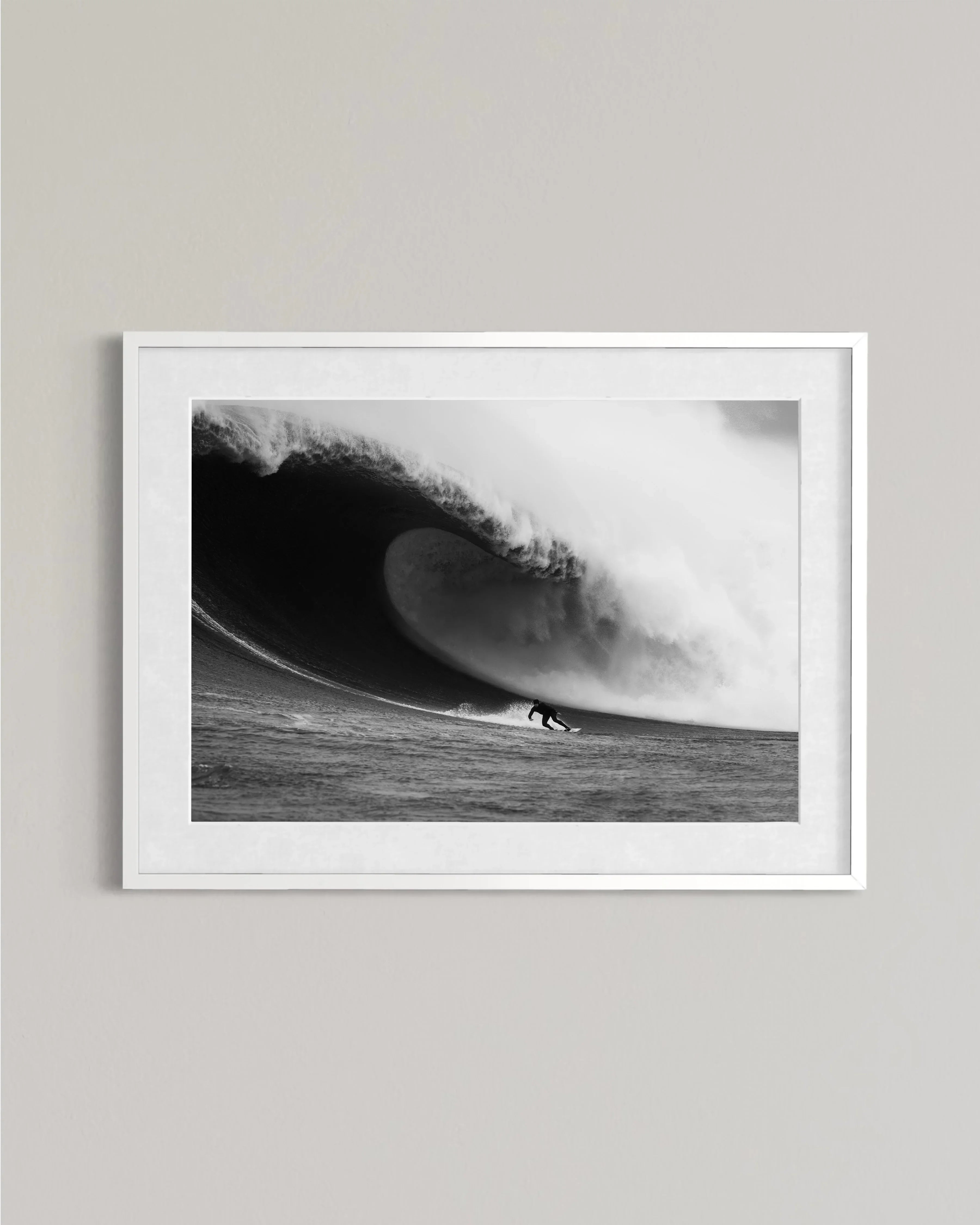Black and white photo of a surfer riding a large wave inside a curling tube