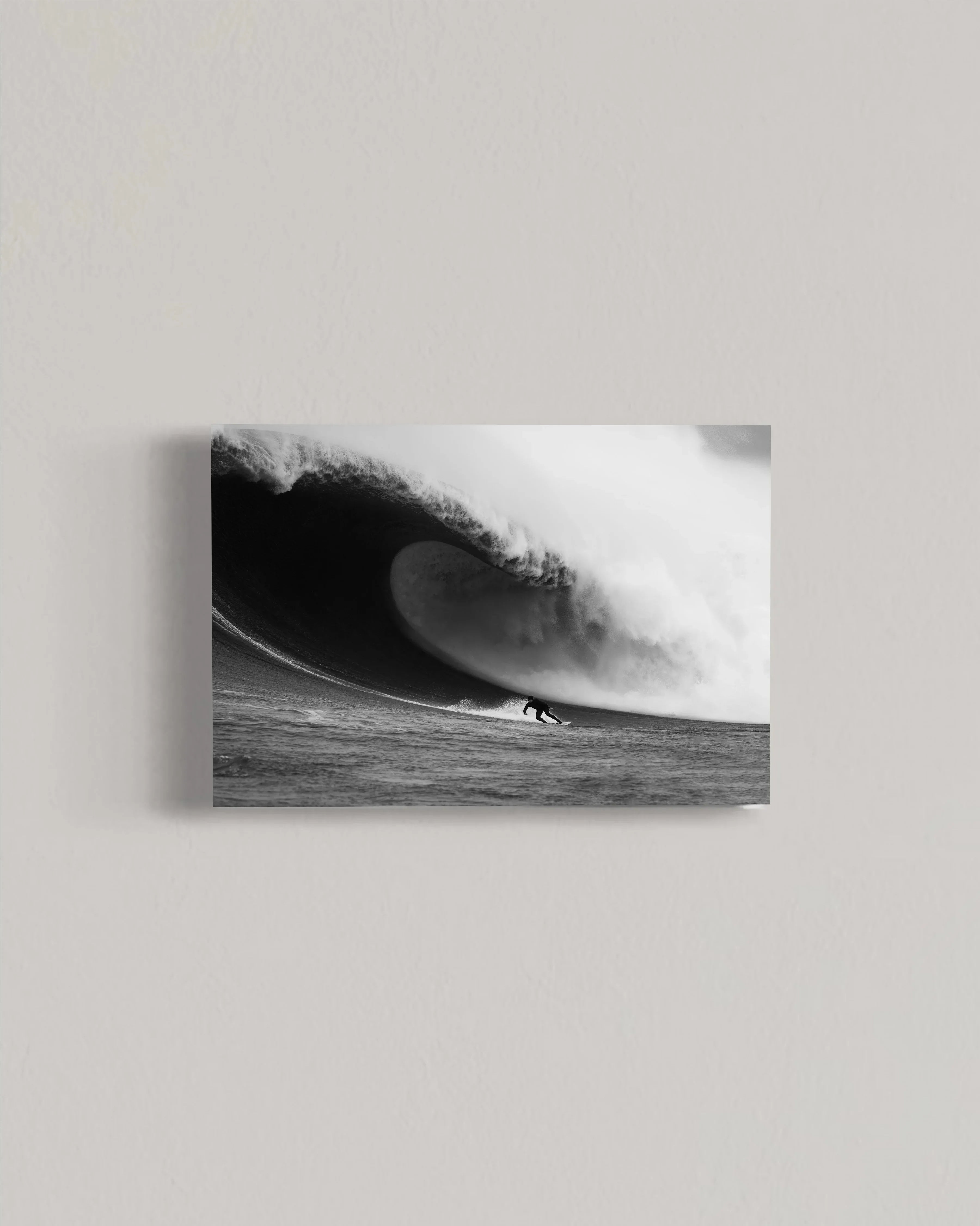 Black and white photo of a surfer riding a large, curling ocean wave