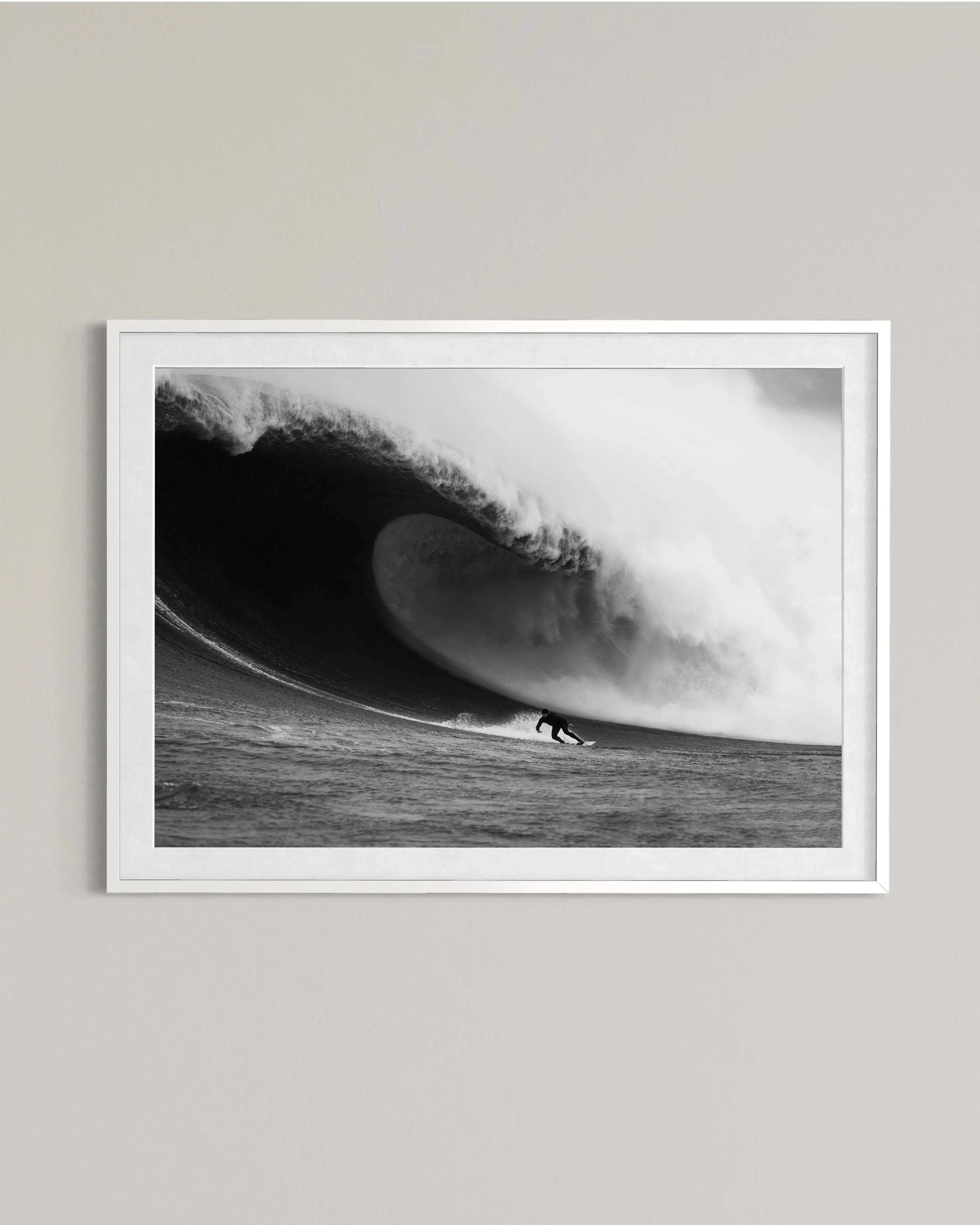 Black and white framed photo of a surfer riding a large barreling wave on the ocean