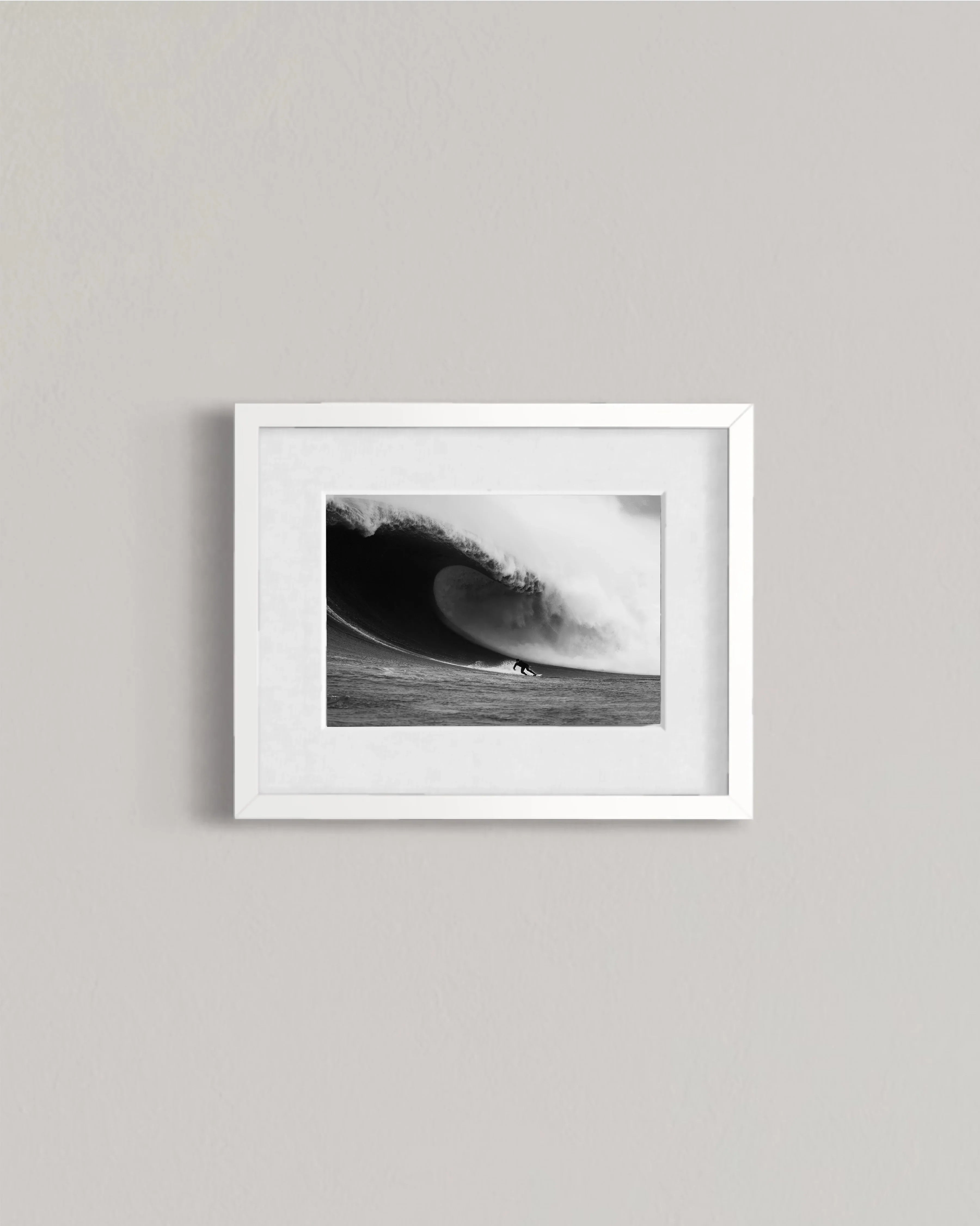 Black and white framed photo of a surfer riding a massive wave on ocean water