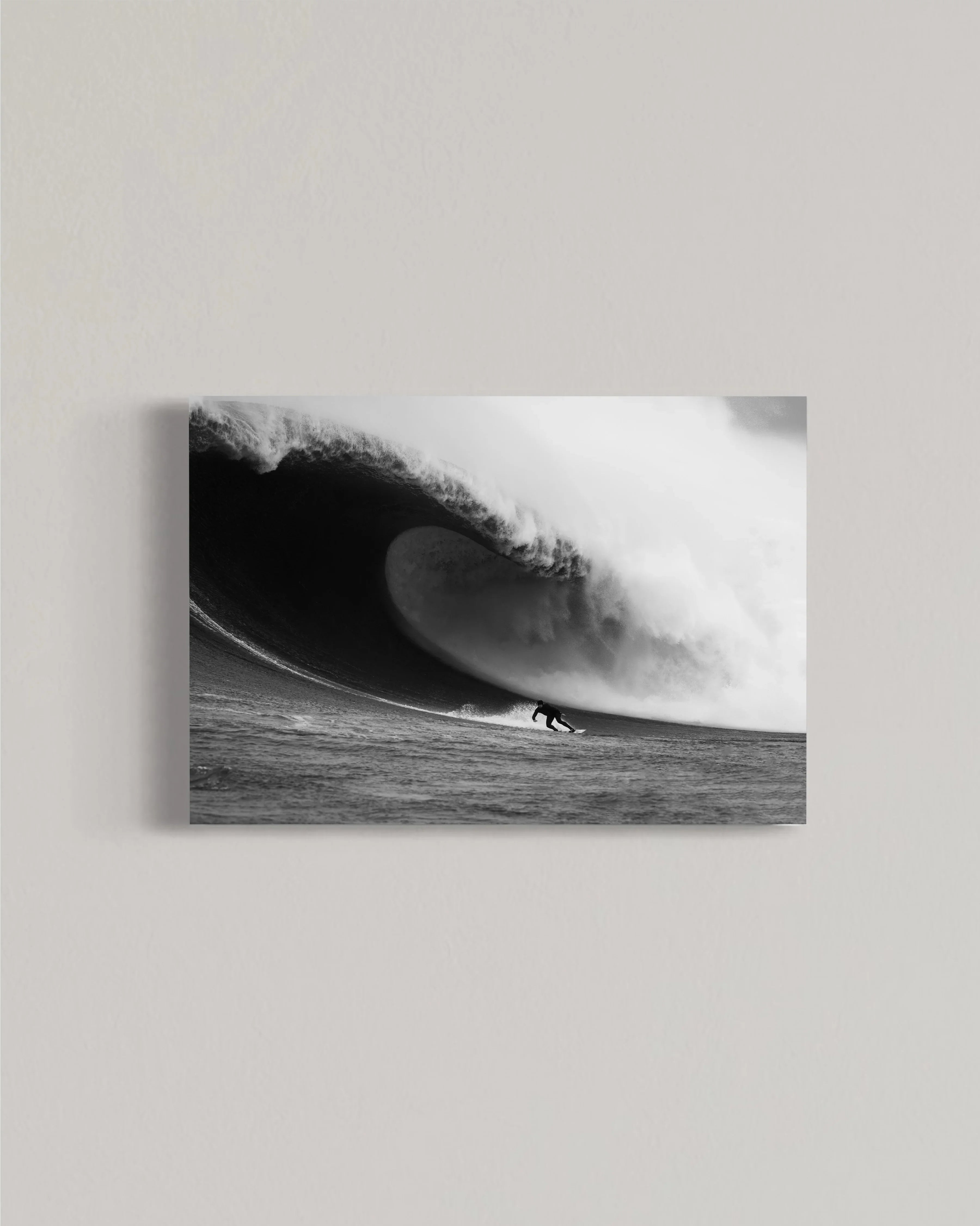 Black and white photo of surfer riding a large dramatic ocean wave