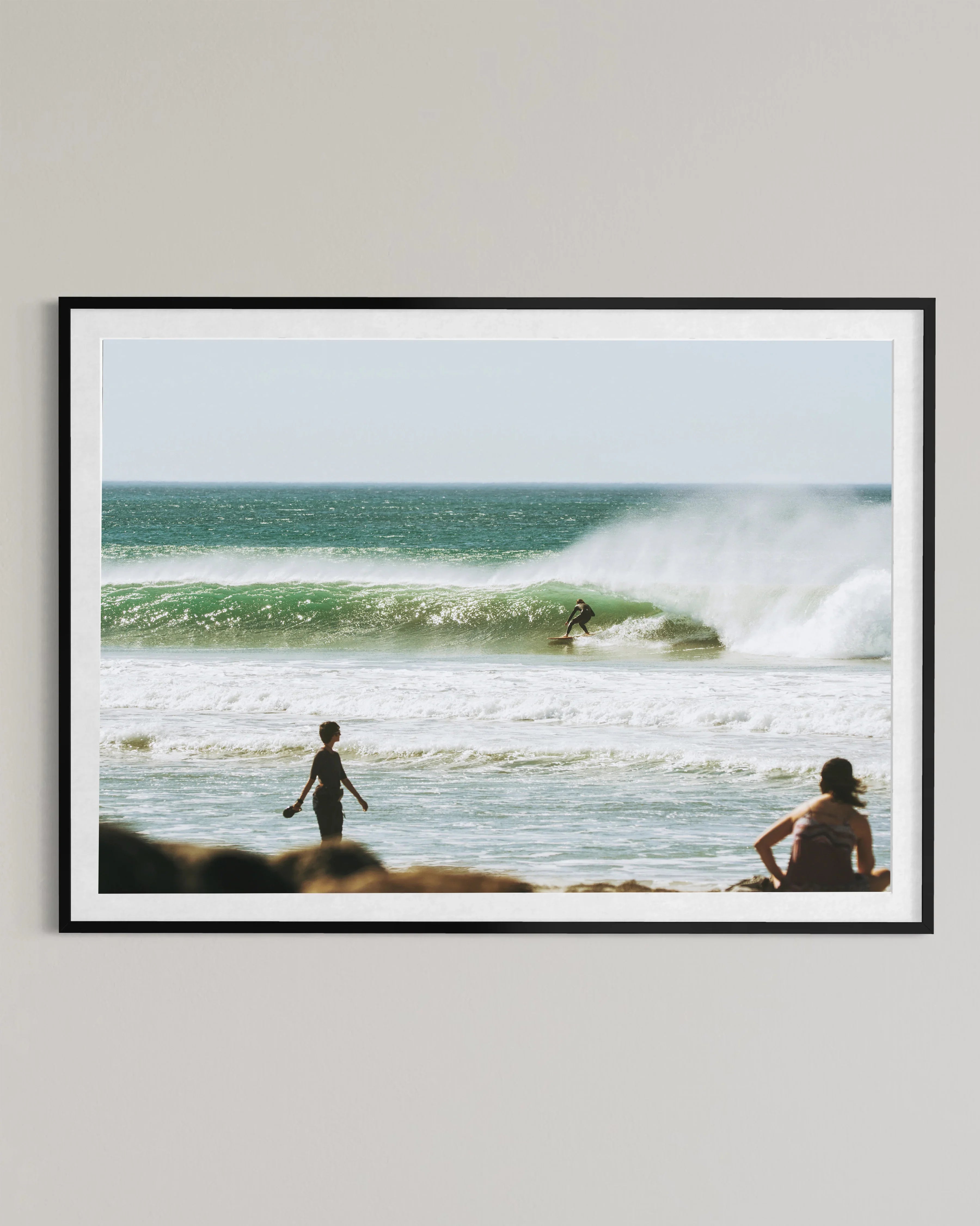 framed beach photo with surfer riding green wave and people watching on shore