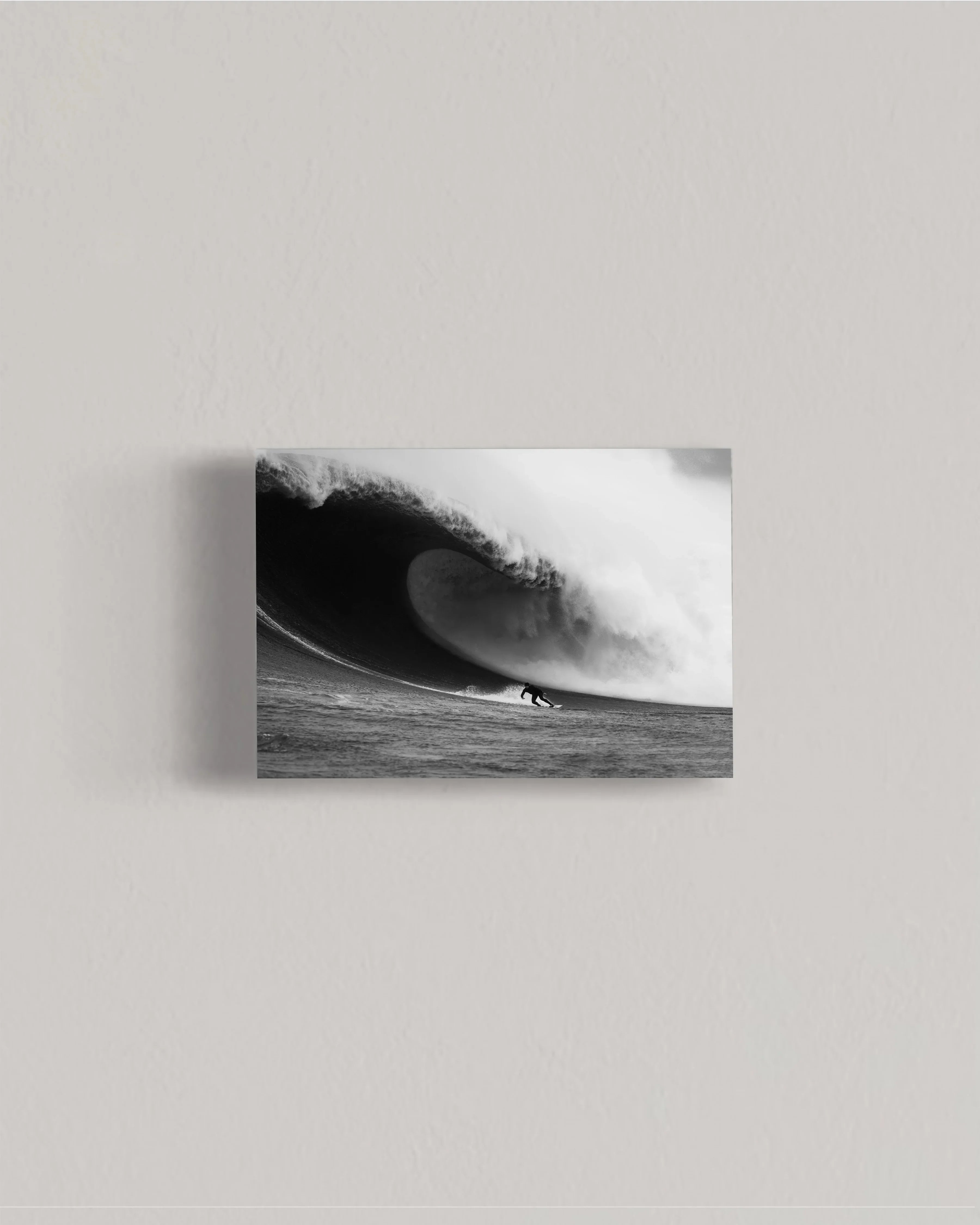 Black and white photo of surfer riding a massive curling ocean wave