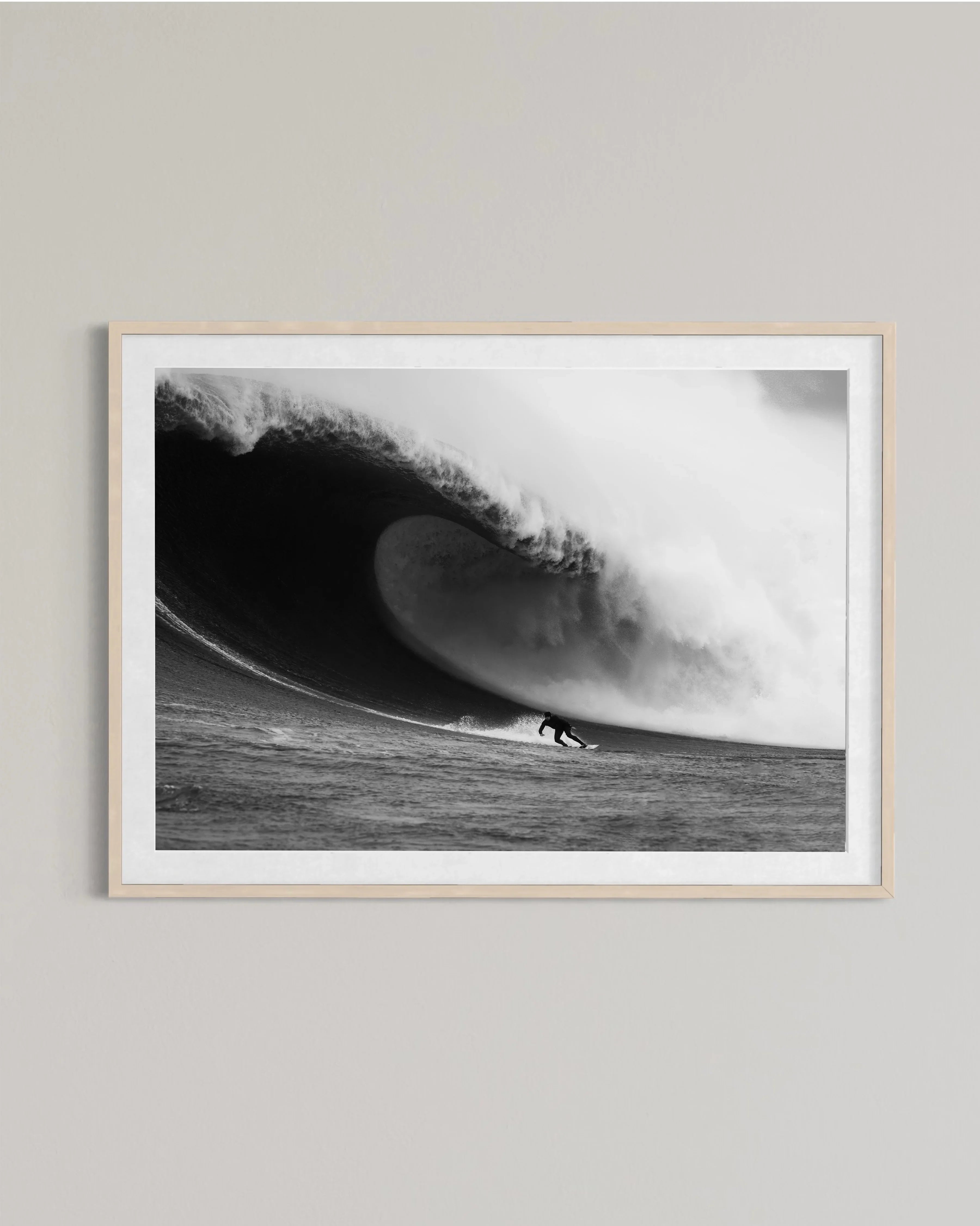 Black and white framed photo of surfer riding inside a large curling ocean wave