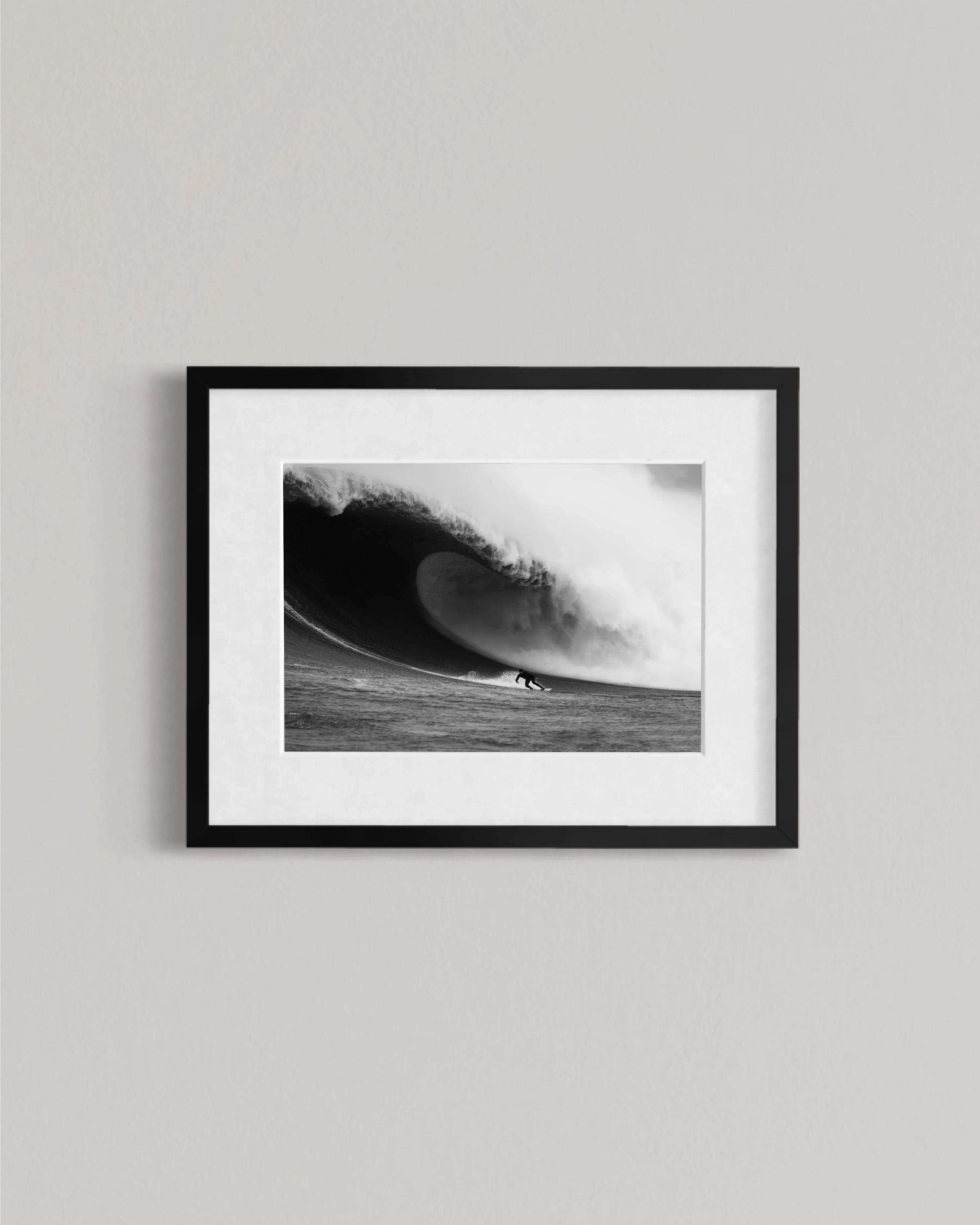 Black and white framed photo of surfer riding large powerful ocean wave